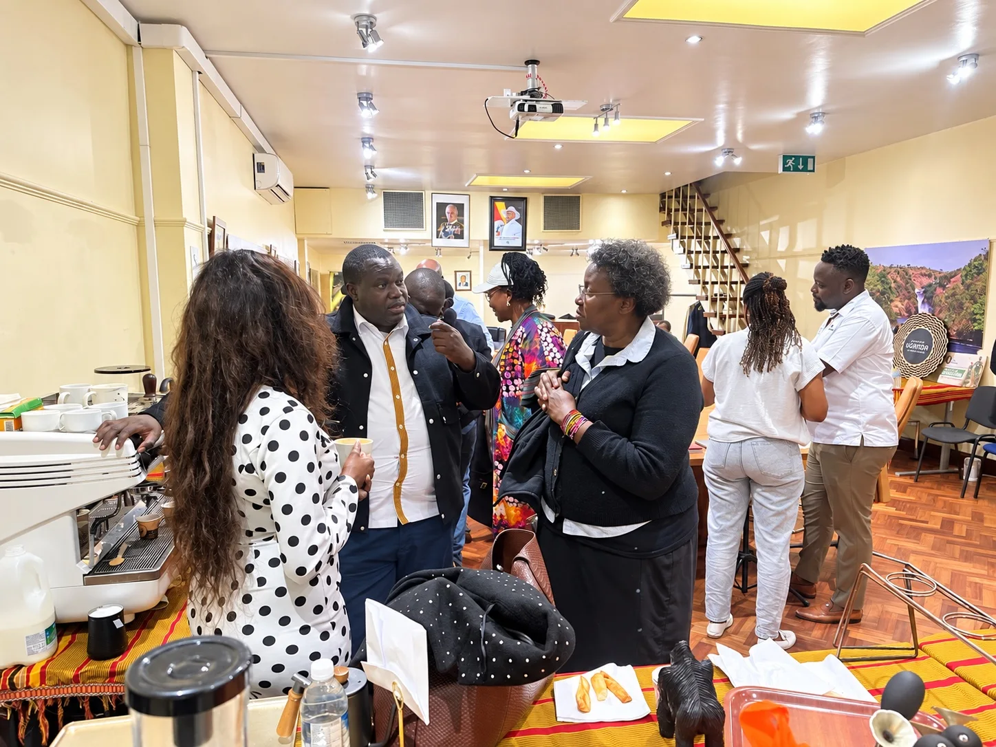 Guests in conversation beside a coffee machine at the Ugandan diplomatic mission in London.